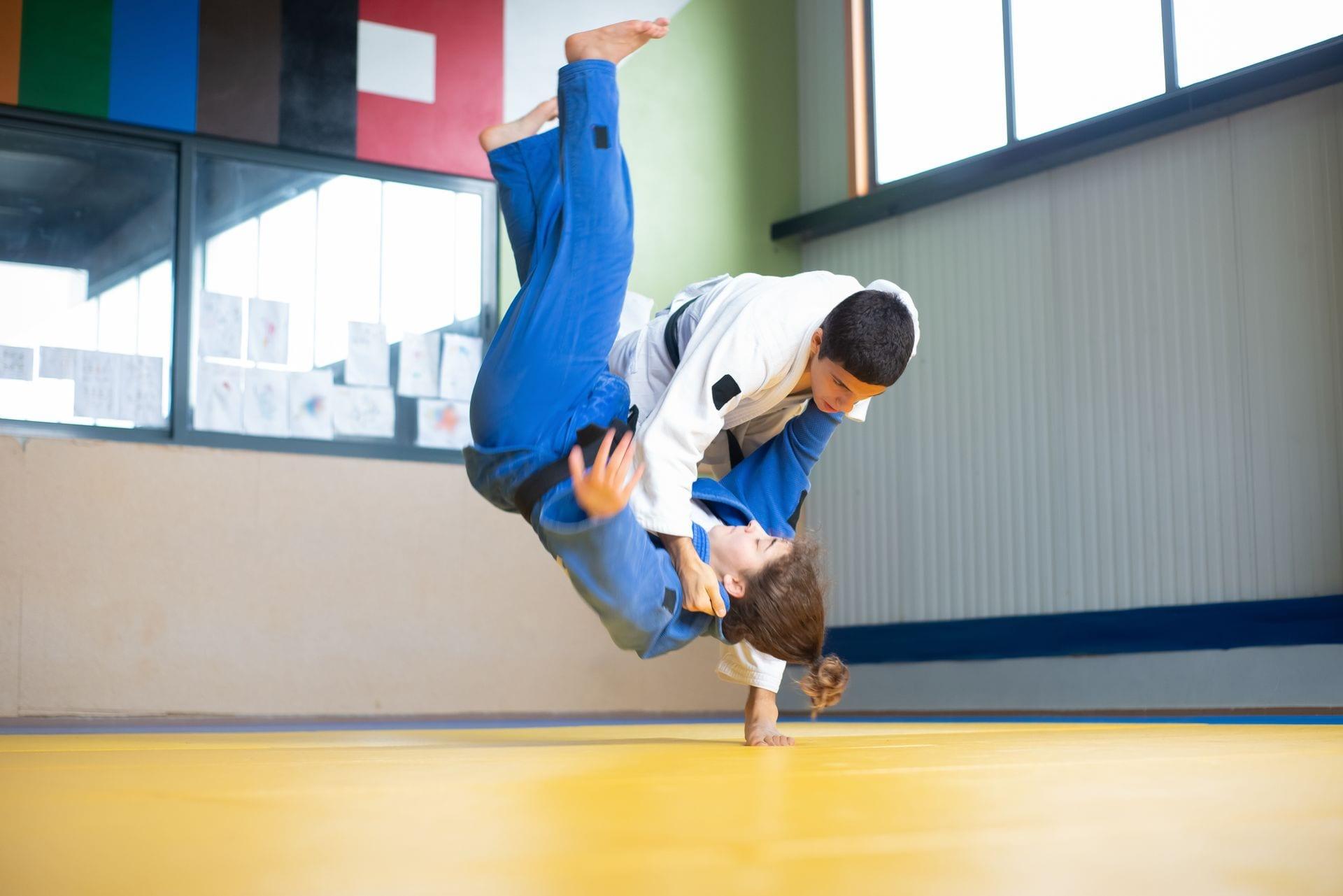 Two judoka mid-throw during training in a dojo